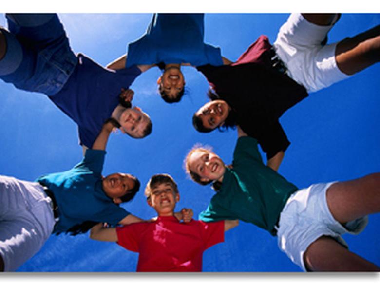 young people in a circle with arms linked (looking down at the camera pointed up in the center)