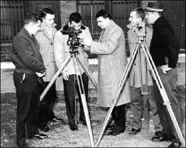 old black and white photo of men gathered around surveying equipment